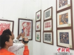 图为6月6日，专程来观展的丁宏和他14岁的女儿丁子卿。丁宏说，特意带着家庭摄像机来拍摄各种作品，希望女儿以剪纸艺术感受到中华传统文化之美。　史静静 摄 - 甘肃新闻