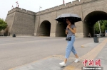 资料图：西安城墙下市民撑伞走过。 中新社记者 张远 摄 - 甘肃新闻