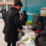 寒风凛冽，在甘肃省白银市白银区街头，一位75岁的老人张菊芳蜷坐在街头卖菜，为病逝的儿子还债。　甘芬 摄 - 甘肃新闻