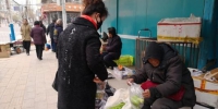 寒风凛冽，在甘肃省白银市白银区街头，一位75岁的老人张菊芳蜷坐在街头卖菜，为病逝的儿子还债。　甘芬 摄 - 甘肃新闻
