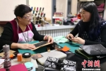 去年上半年，60岁的李丽和53岁的李霞姐妹俩在家人的提议下，开办手工皮具制作工作室，当起时尚创客，如今她们是生意越来越好。图为指导顾客做皮具。　刘玉桃 摄 - 甘肃新闻