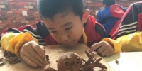 实验三小陶艺课上，五年级学生王博文在自己作品上用木刀再加工，“树干”上显现出一条条纹路。　张婧 摄 - 甘肃新闻