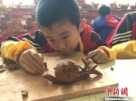 实验三小陶艺课上，五年级学生王博文在自己作品上用木刀再加工，“树干”上显现出一条条纹路。　张婧 摄 - 甘肃新闻