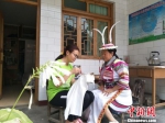 图为志愿者与甘肃陇南文县白马藏族妇女一起制作特色文化产品。　李铭垣 摄 - 甘肃新闻