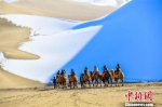 图为11月15日，游客在雪后的甘肃敦煌鸣沙山月牙泉景区欣赏大漠雪景。　王斌银 摄 - 甘肃新闻