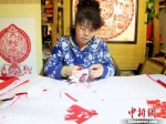 图为敦煌剪纸传承人何克风在月牙泉小镇的剪纸店里认真创作。(资料图) 田明君 摄 - 甘肃新闻