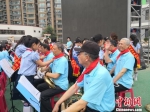 图为小学生为前来进行乐器表演的七里河区老年大学学员佩戴红领巾。　杨娜 摄 - 甘肃新闻