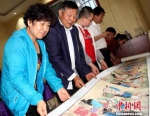 图为李世荣向绘画爱好者展示《芮鞫农贸图卷》。　郭惠民 摄 - 甘肃新闻