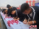 图为民众在拒毒横幅上签名。　崔琳 摄 - 甘肃新闻