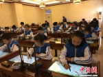 图为小学生正在使用智能书法系统练习写书法。(资料图) 林鹏 摄 - 甘肃新闻