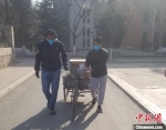 图为阿布(左)和泽广(右)在校园中用三轮车运送待发放中药。受访者供图 - 甘肃新闻