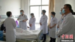 天津医生陈辉(左二)在病房和环县中医医院医生探讨患者病情，确定最佳的诊疗方案。　李文 摄 - 甘肃新闻