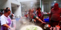 图为文县碧口镇妇女在安置点烹饪“大锅饭”，并发放给民众。　王小勇 摄 - 甘肃新闻