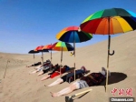 每年仲夏时节，在甘肃酒泉金塔县金嘉路7公里处的沙漠边缘，一大批游客或躺、或埋、或睡，将身体藏进滚烫的沙子里，体验沙疗带来的神奇疗效。(资料图) 卢玉 摄 - 甘肃新闻