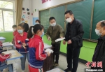 图为冯继(右三)和老师给学生发放防疫物资。(资料图)受访者供图 - 甘肃新闻