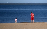 在天津市滨海新区东疆港人工沙滩，家长和小朋友一起背手望向大海（6月5日摄）。新华社记者 李然 摄 - 人民网
